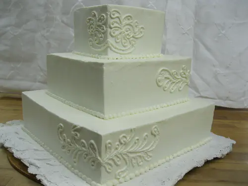 Wedding cake: Square #1. Buttercream, “lace” piping to match the lace on the wedding dress.